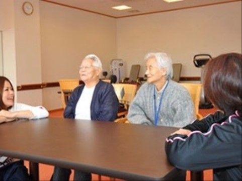 椅子に座って楽しそうにスタッフとお話しするご入居者様