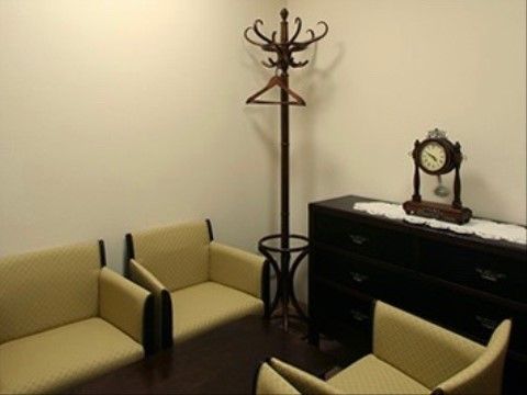 室内にはソファが向かい合って設置され、ハンガーが設けられている。アンティークな家具の上には時計が置かれている。