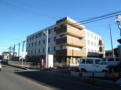 敷地内に広い駐車スペースのある、4階建ての施設の外観