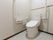 トイレは全面フラットなフロアに設置されている。手すりは座って右側の壁に1つと、背面の壁に可動式のものが1つある。