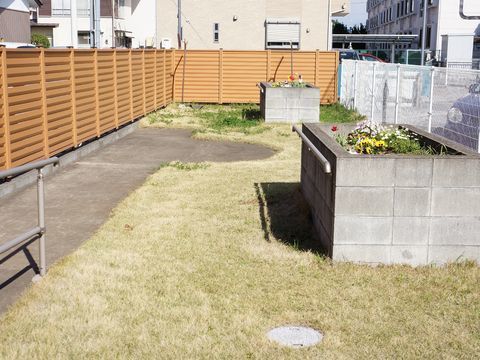 芝生のある空間の庭である。花壇が手前と奥に1つずつ設置されている。また、左側のフェンスは木目調で目隠しとなっている。