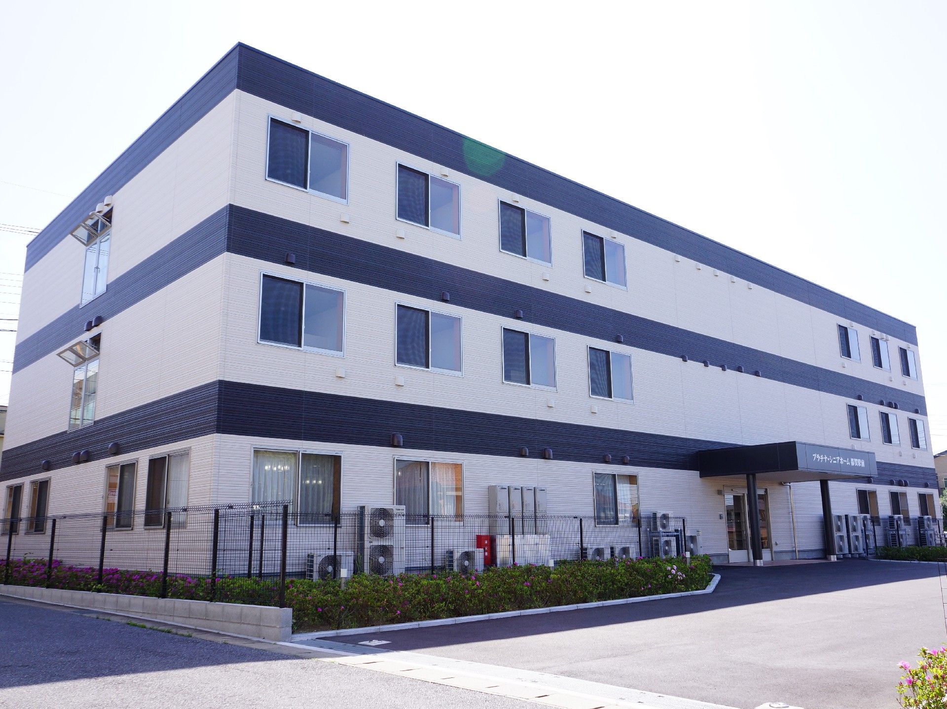 建物周辺に花壇が設けられている、3階建てのサービス付き高齢者向け住宅の外観。