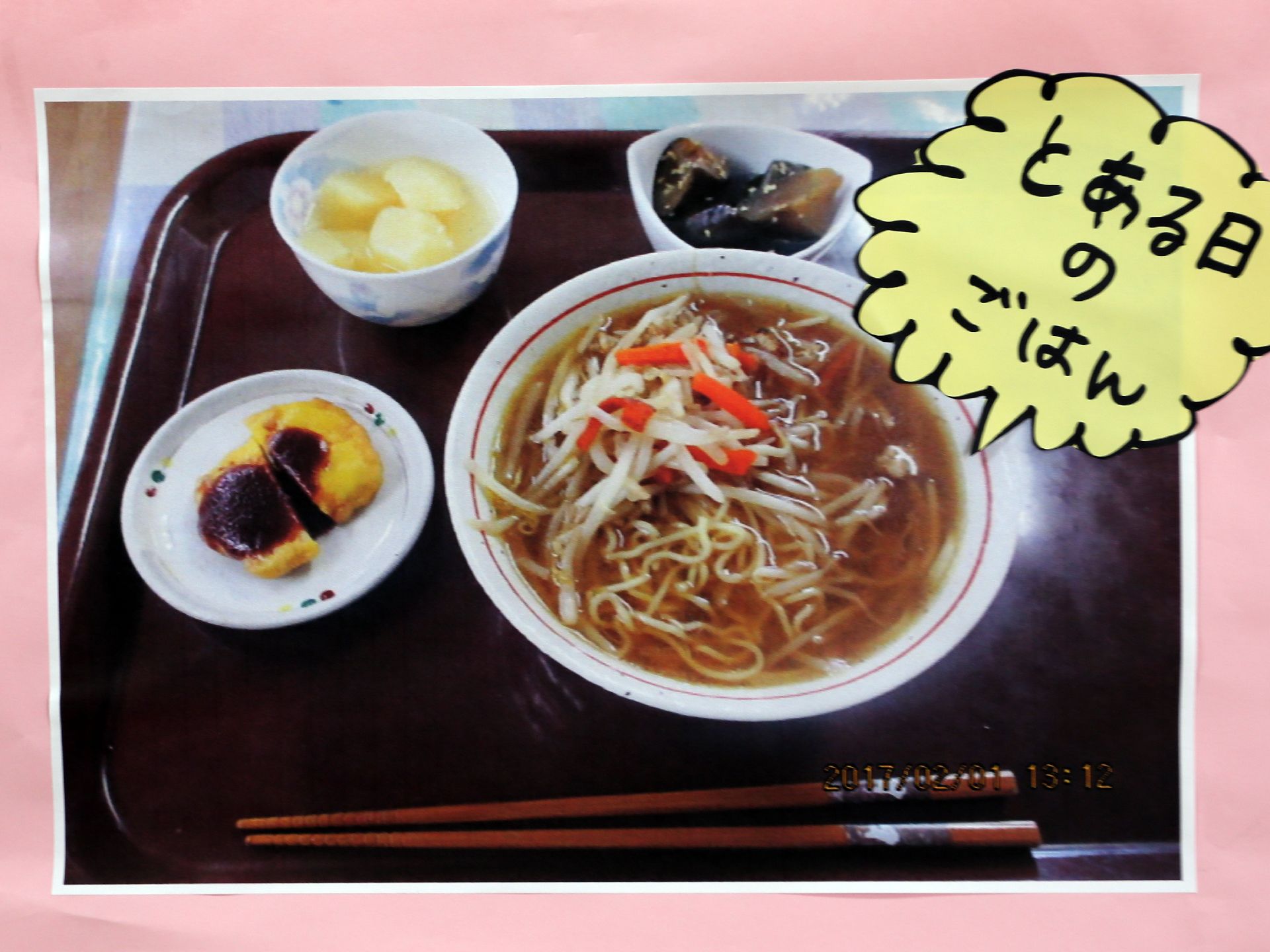 食事内容の写真がプリントアウトされている。丼に入った麺類を中心に、副菜が3品並んでいる。とある日のごはん、とコメントがついている。