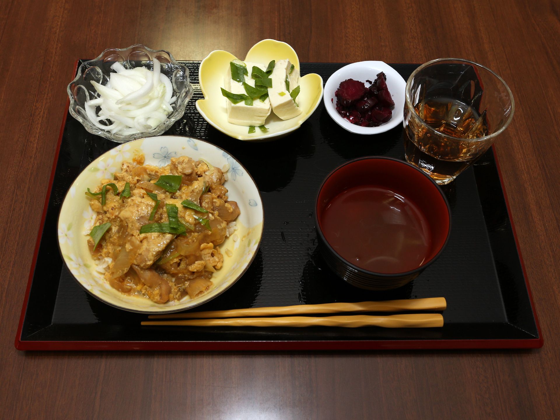 親子丼のような丼物、冷奴、漬物など様々なメニューがトレーに並んでいる。栄養バランスや彩りなどを考えて作られている料理である。