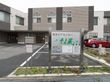 施設の前には駐車スペースがある。道路の通りから見えるように施設の種類と施設名が表示されている。夜にはライトアップされる。