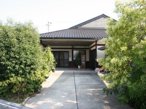 両側に生い茂った緑の木が生えている通路の先にある施設の外観
