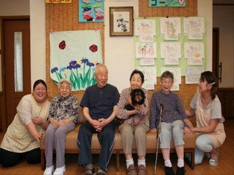 装飾された壁の前で、楽しそうにほほ笑むご入居者様とスタッフ