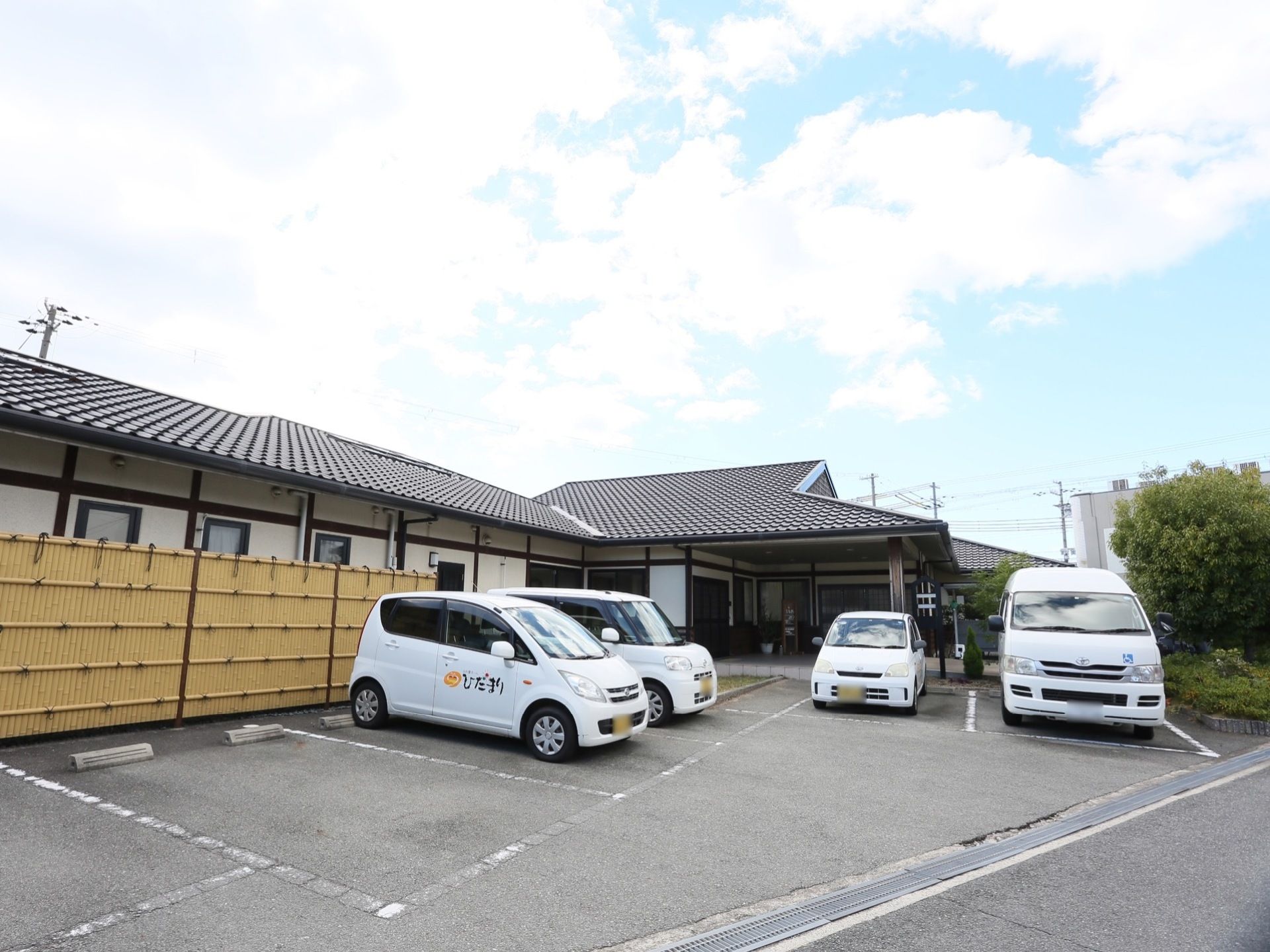 施設敷地内に完備されている駐車場である。施設名称とロゴマークが明記された白い施設専用車やワゴン車が停車している。