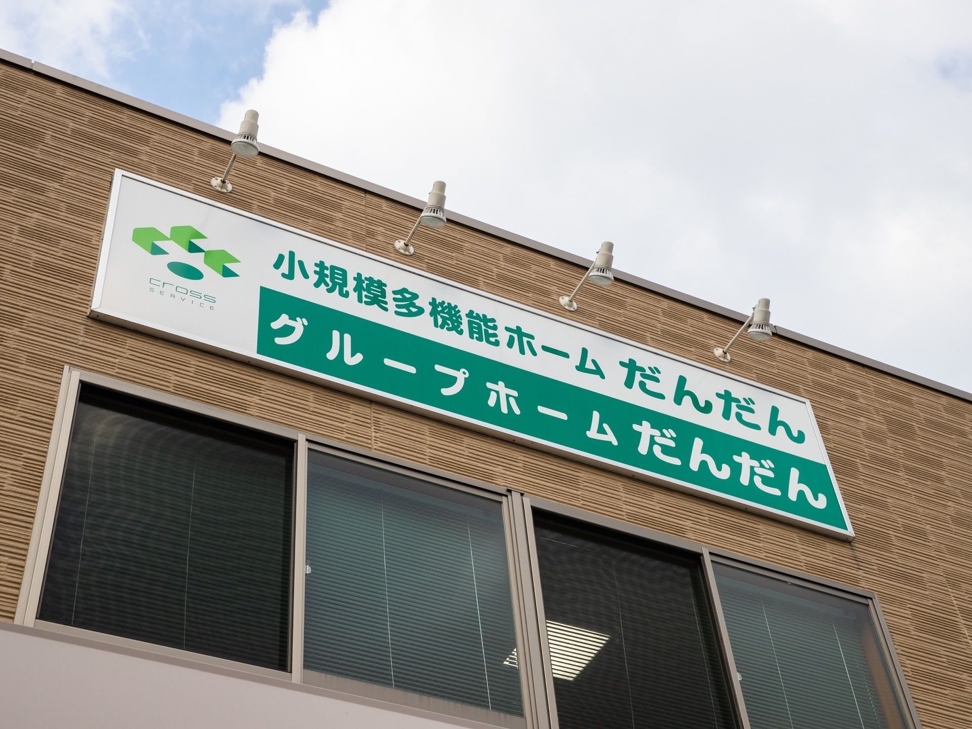 施設の名称が大きな文字ではっきりと書かれた看板が建物上部に掲示されている。看板の上部にライトが４つついている。
