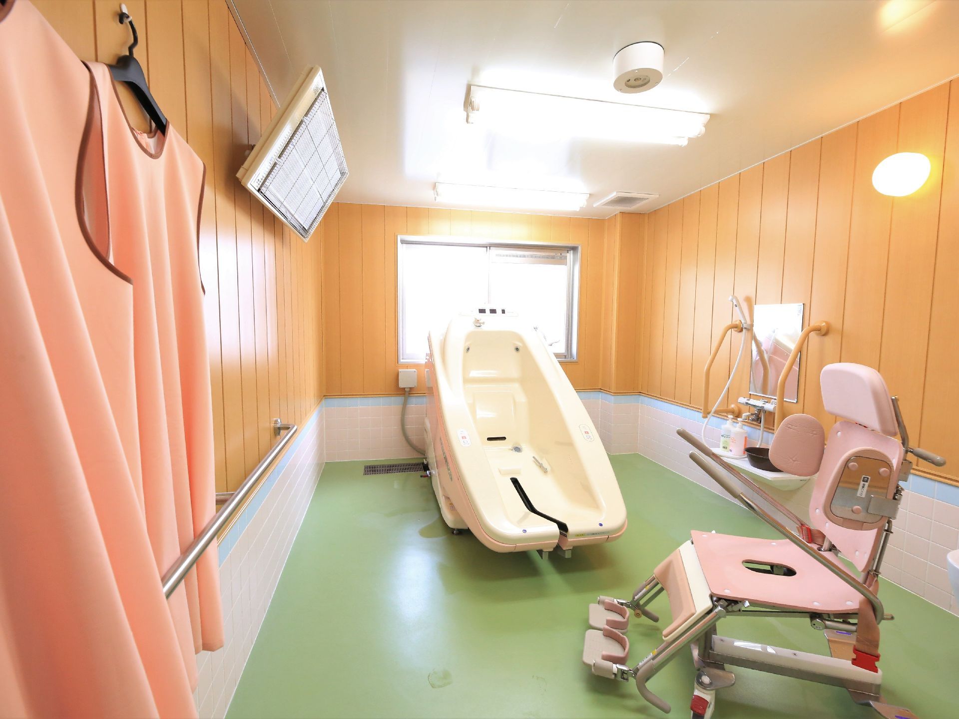 機械浴室内は広く、照明器具がたくさん設置されている。陽の光も差す明るい空間である。専用の車椅子と浴槽が準備されている。