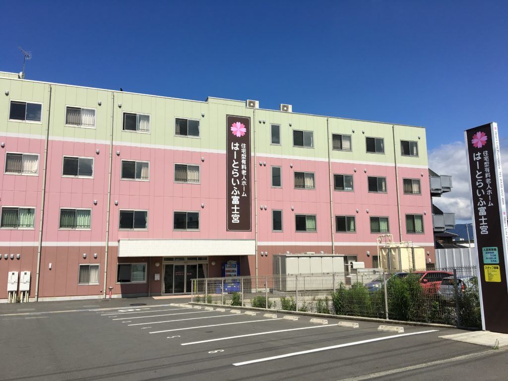 施設の前には広い駐車スペースが設けられている。見学も、入居者様の面会も車で来ることができる。道路沿いに看板がある。