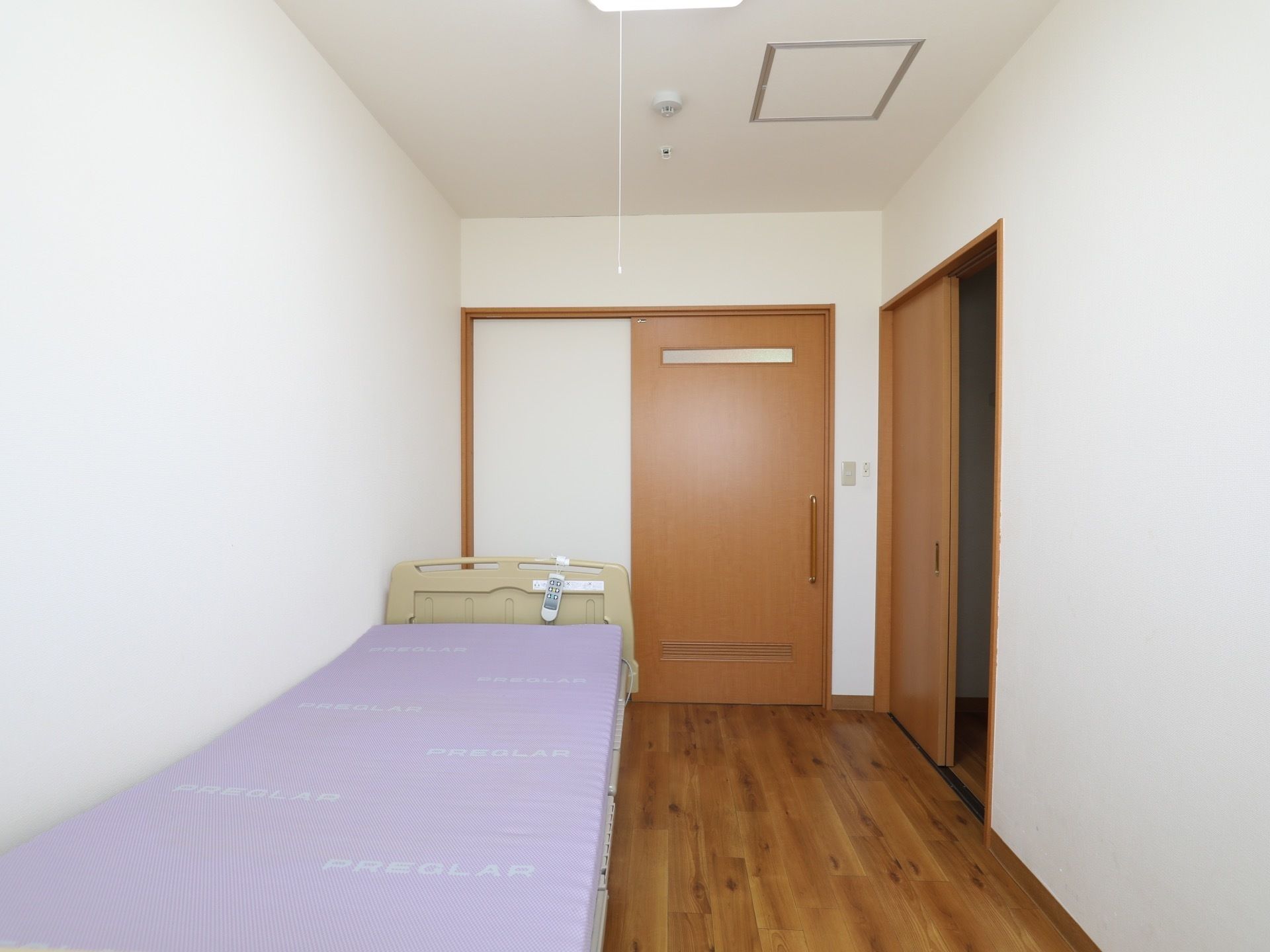 縦長の居室である。壁際にベッドが設置されている。そのベッドは電動式である。向かい側にはトイレ用の個室が設けられている。