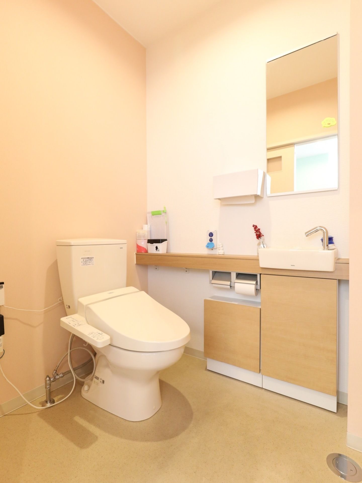 温水洗浄便座付きの、明るく広いトイレである。床はフローリングで、鏡付きの洗面台が取り付けられている。