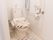 暖房洗浄機能付便座を採用したトイレは、手摺りが立ち座り姿勢をガードしてくれる。壁には緊急用呼び出しボタンが目立つ様に設置されている。