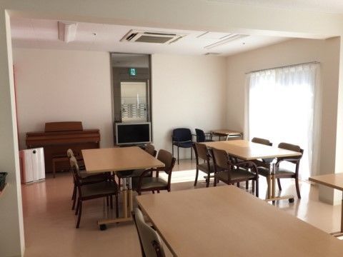 ガラス戸から射し込む光は、お部屋の空間を明るく照らしている。４人掛けのテーブルを配置し、天井にエアコンを設置している。