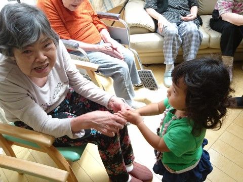 入居者様が小さな女の子と握手をし、思わず笑顔になっている様子