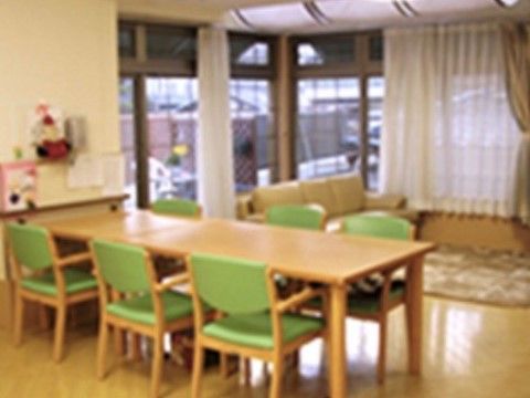 長テーブルと6脚の椅子がある。3人がけのソファーの前にはカーペットが敷かれている。テーブル付近には可愛らしい置物がある。