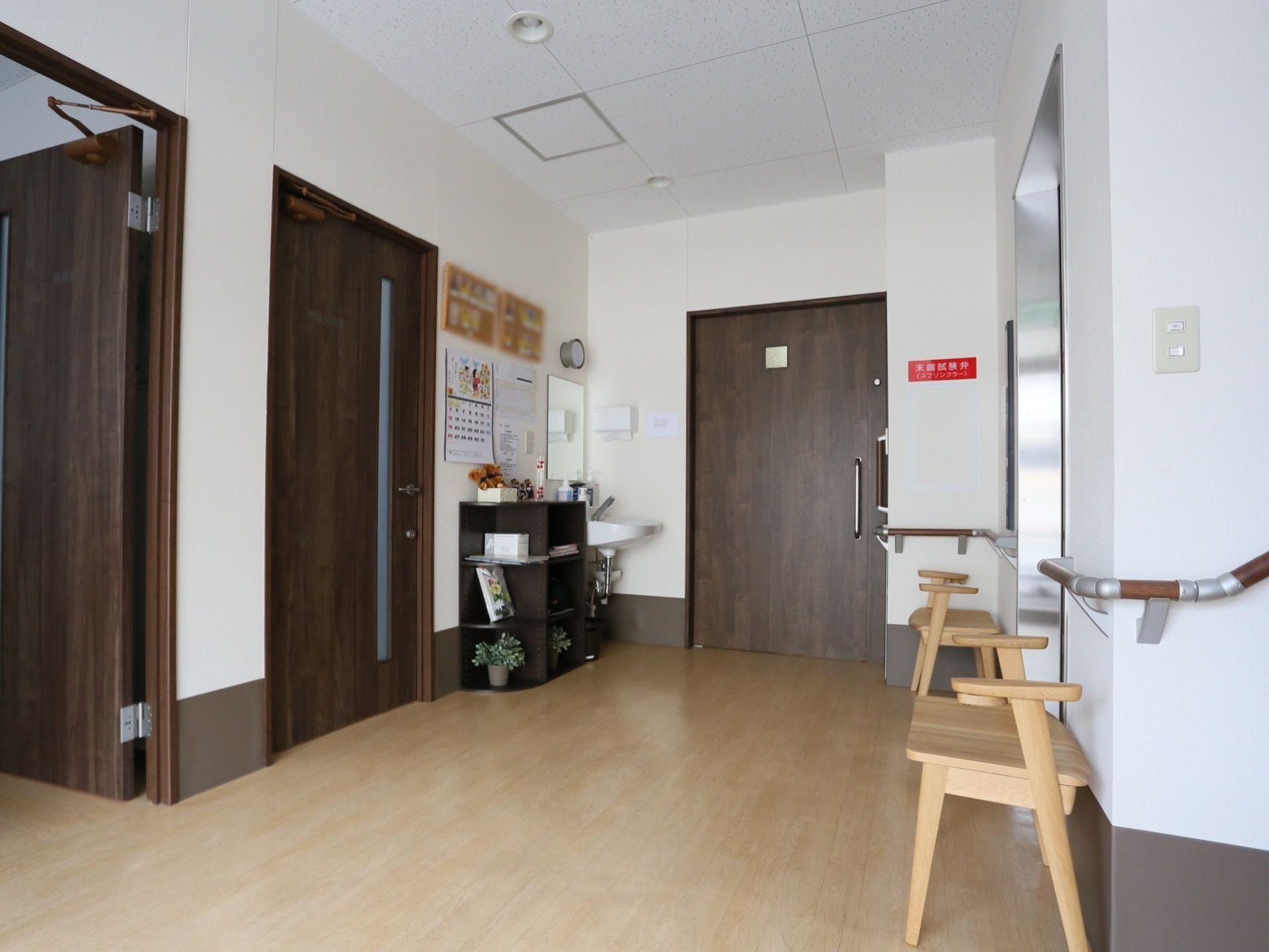 床は明色系、建具は暗色系にデザインされている。壁伝いに手すりを設置。通路の隅には収納家具が置かれている。