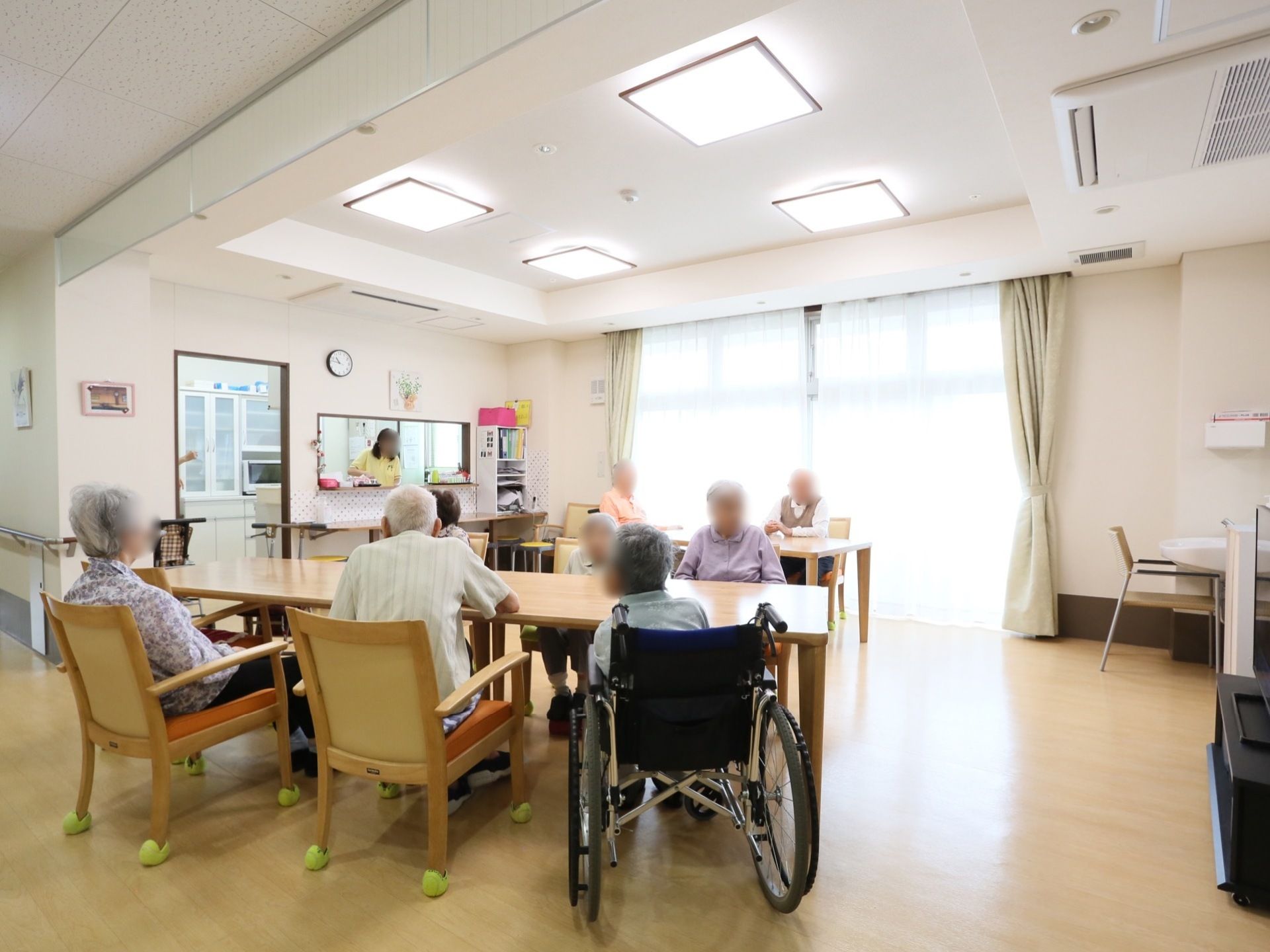 男女交え、入居者様同士でくつろぎの時間を過ごしている。車椅子をご利用の方も快適に移動できる、広々とした空間である。