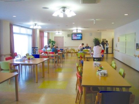 明るく開放的なリビングである。天井にデザイン性のある照明が複数設置されている。正面の壁には大きなテレビが取り付けられている。