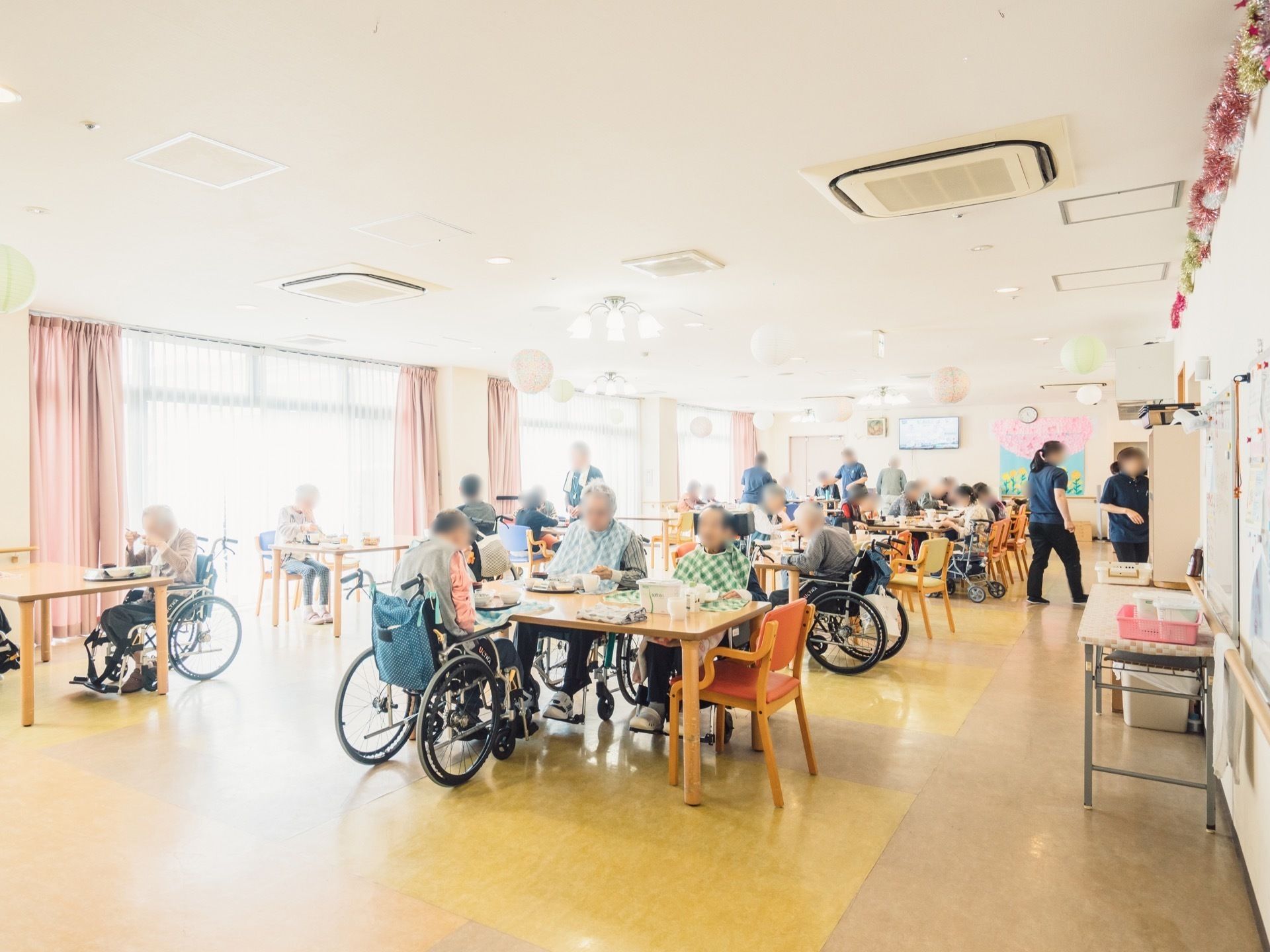 明るく開放感のあるリビングで、楽しそうに食事を取っている入居者様とサポートするスタッフ
