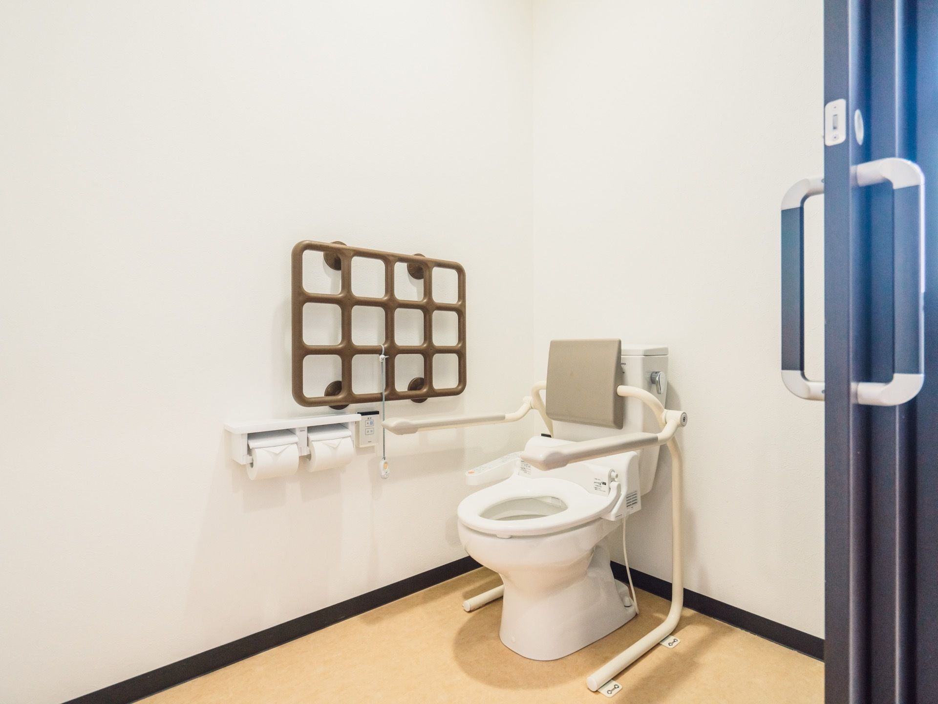 トイレのドアは引き戸で大きく開閉する。便座には背もたれと、ひじ掛けが設置されているのでゆっくりと座れる。