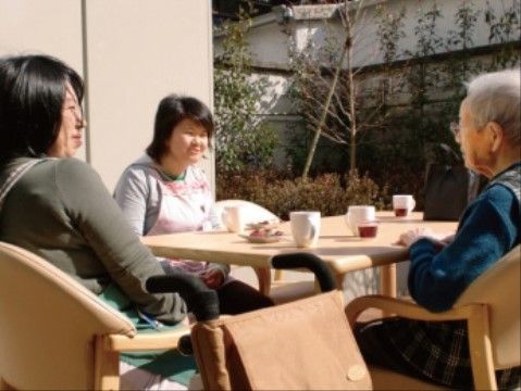 日当たりの良いテーブルでお茶を囲み語らう、スタッフと入居者様
