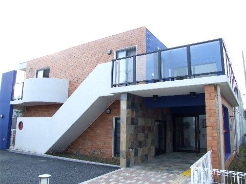 出入り口は段差がなく、レンガ調と青い色の塗装の２階建ての外観