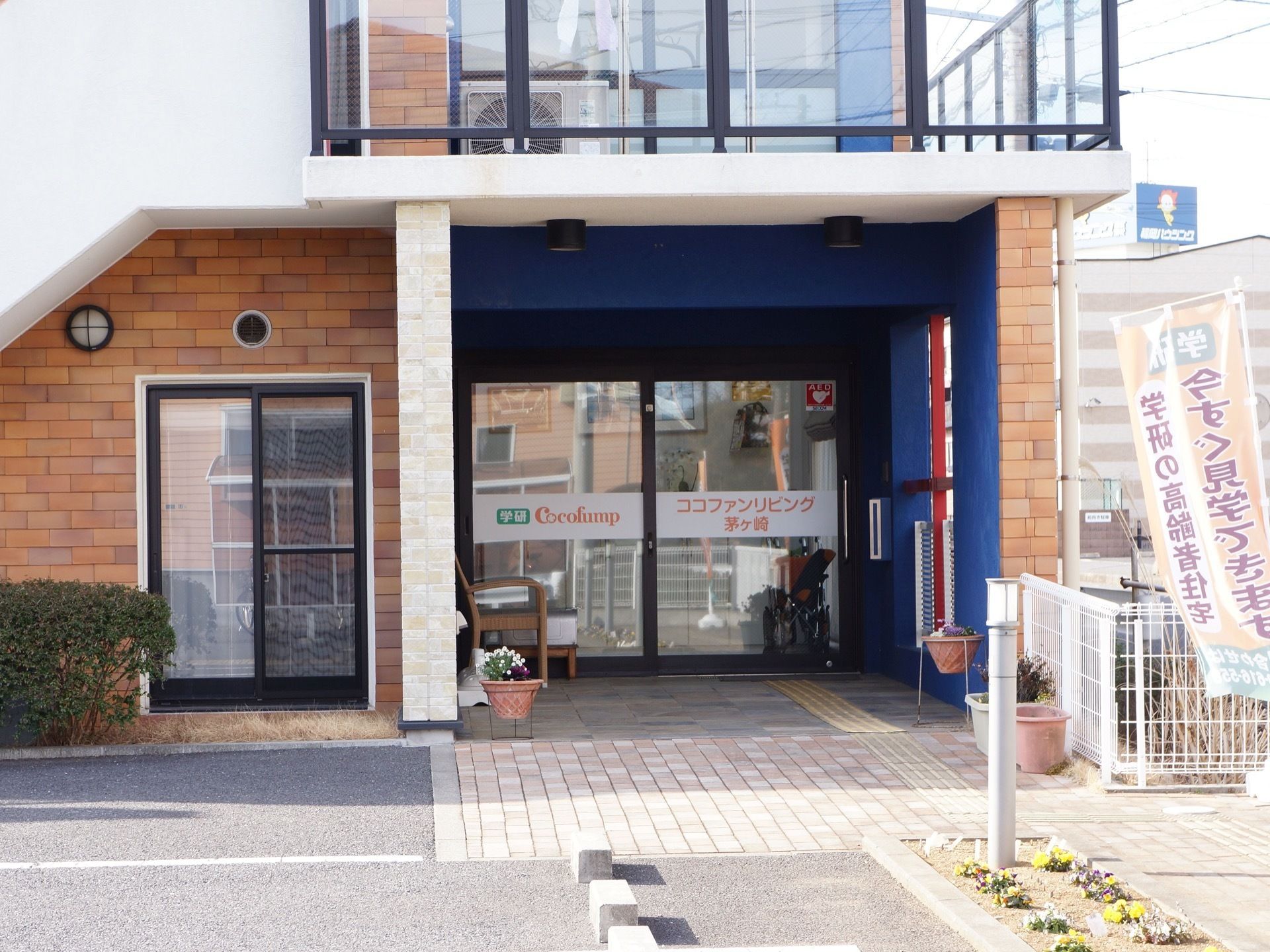 ２階建ての建物で、２階のバルコニーはガラス張りになっている。玄関前にはいつでも見学できることをアピールする旗が掲げられている。