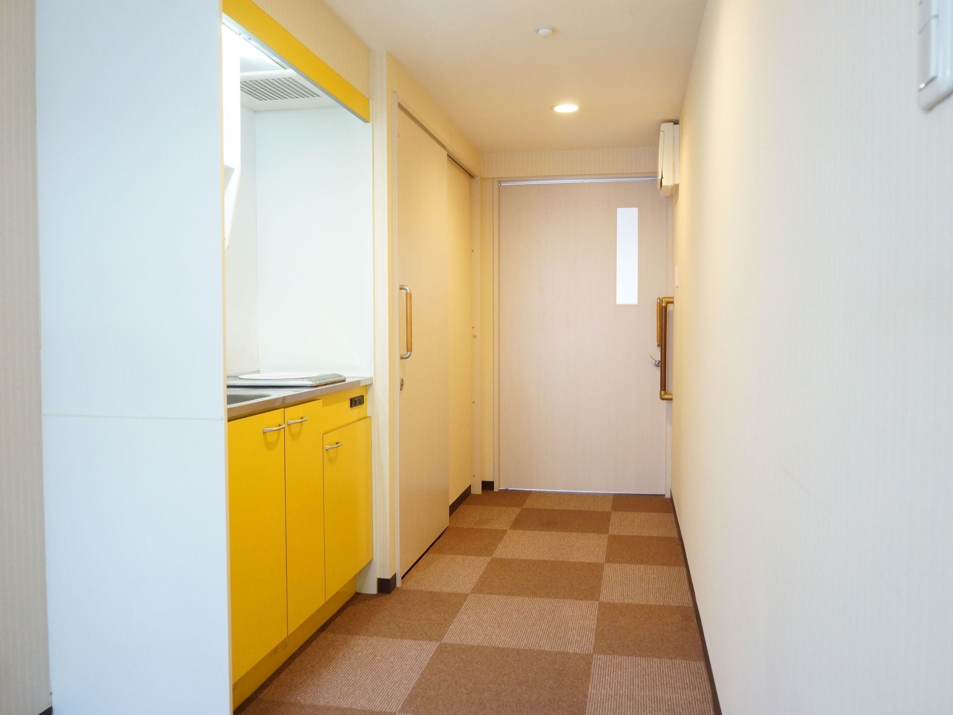 白を基調とした居室に、黄色のミニキッチンがある。簡単な料理ができ、自由にプライベートの時間を楽しむことができる。