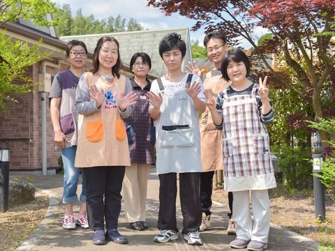 自然豊かな敷地内で、笑顔でポーズをとるスタッフたちの様子