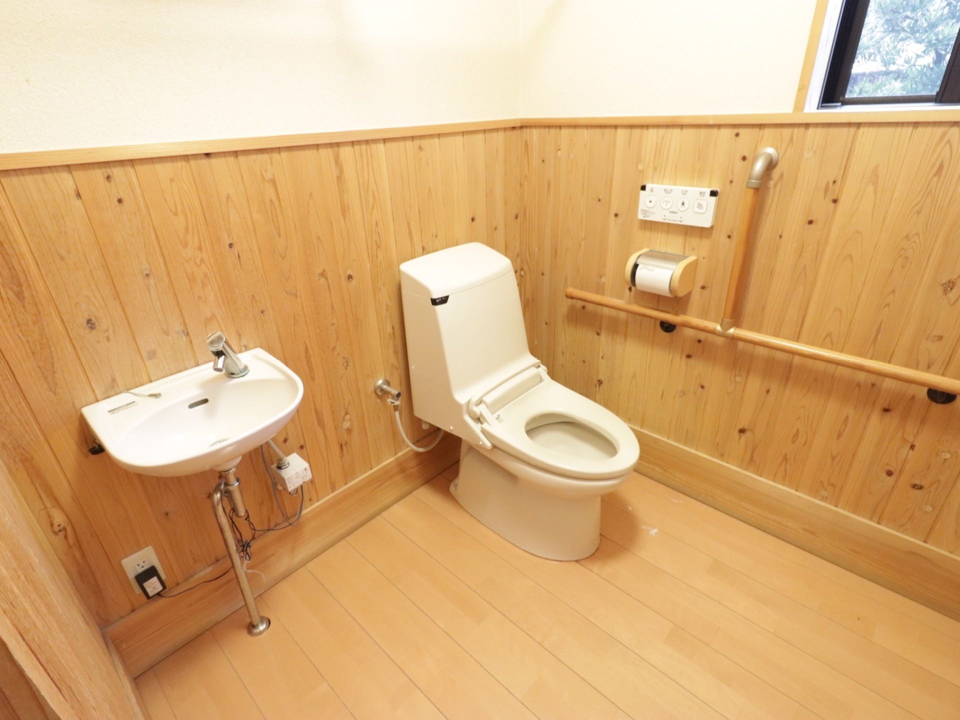 広々としたスペースの個室である。温水洗浄便座の付いたトイレで、個室内には手すりや洗面台が設置されている。