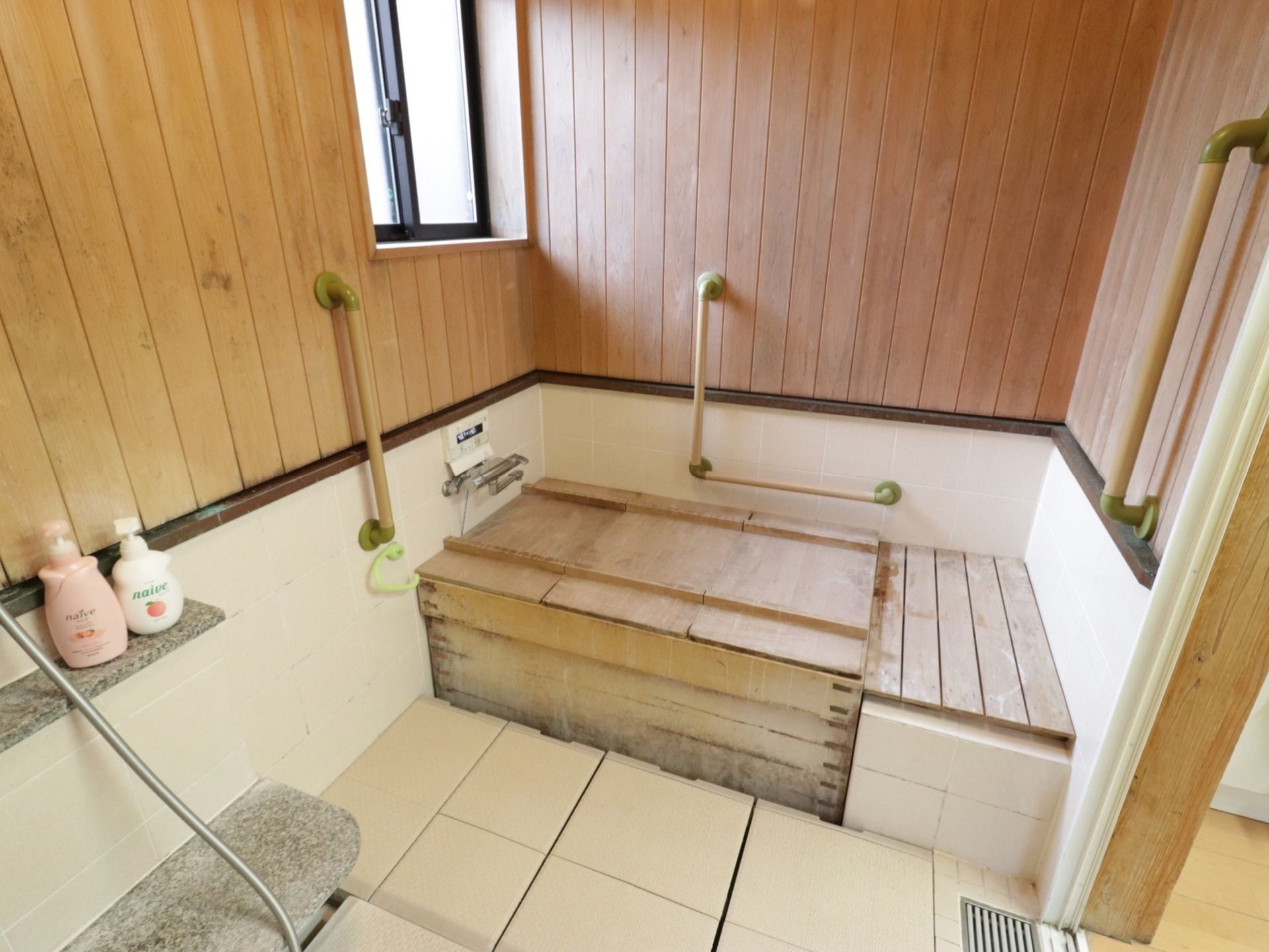 壁や浴槽に木材を使用してある浴室である。またシャンプーなどの小物を置く台は石でできている。壁に手すりを設けている。