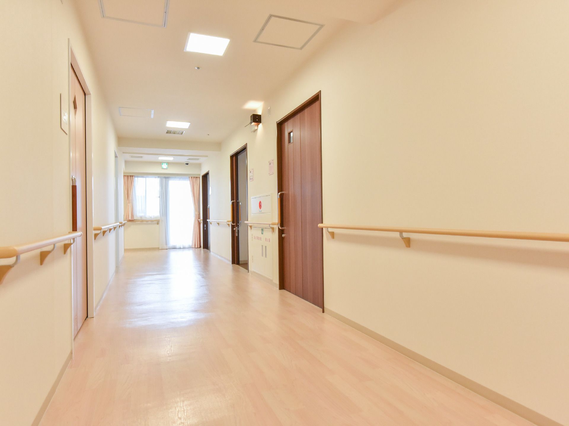 廊下の床は全面段差なく整えられている。両側の壁には部屋のドアが並び、ドア以外の部分には全て手すりが取り付けられている。