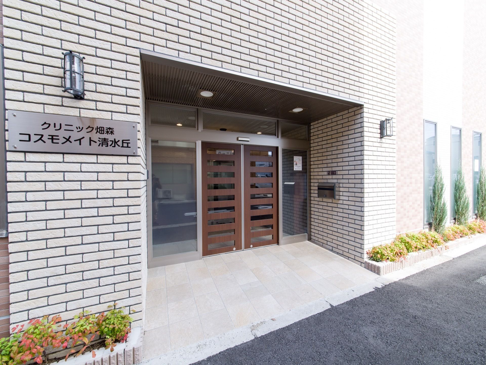 施設名を記載したプレートが玄関前の壁に設置されている。照明も設置され、夜でも玄関前は明るくなっている。