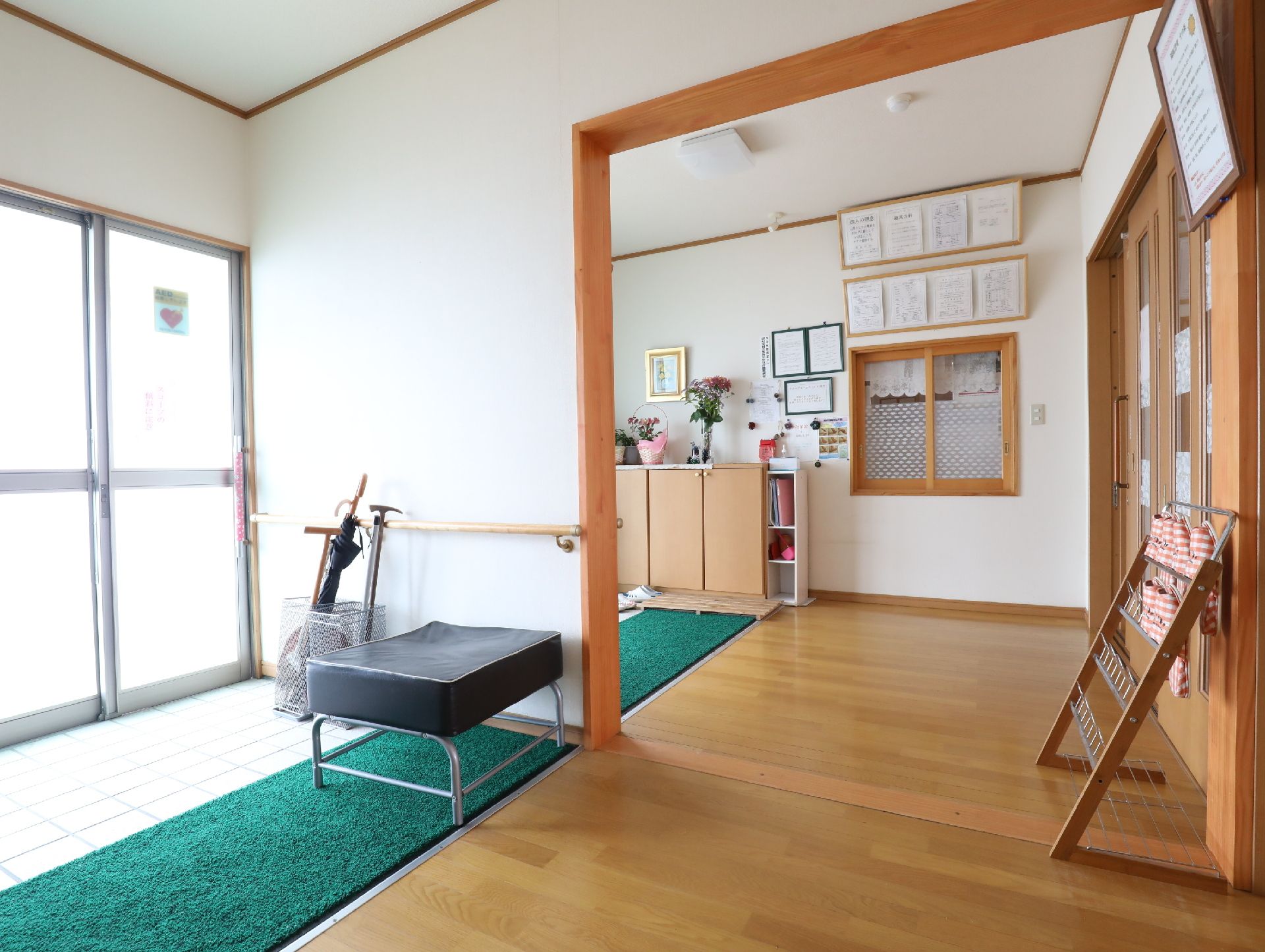 緑のマットや椅子が設置されたバリアフリー設計の玄関
