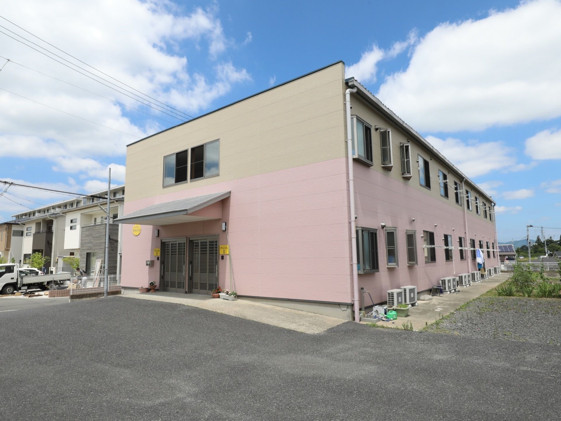 施設の外壁は淡いピンク色とベージュ色のツートンカラーになっており、道路から容易に確認することができる。