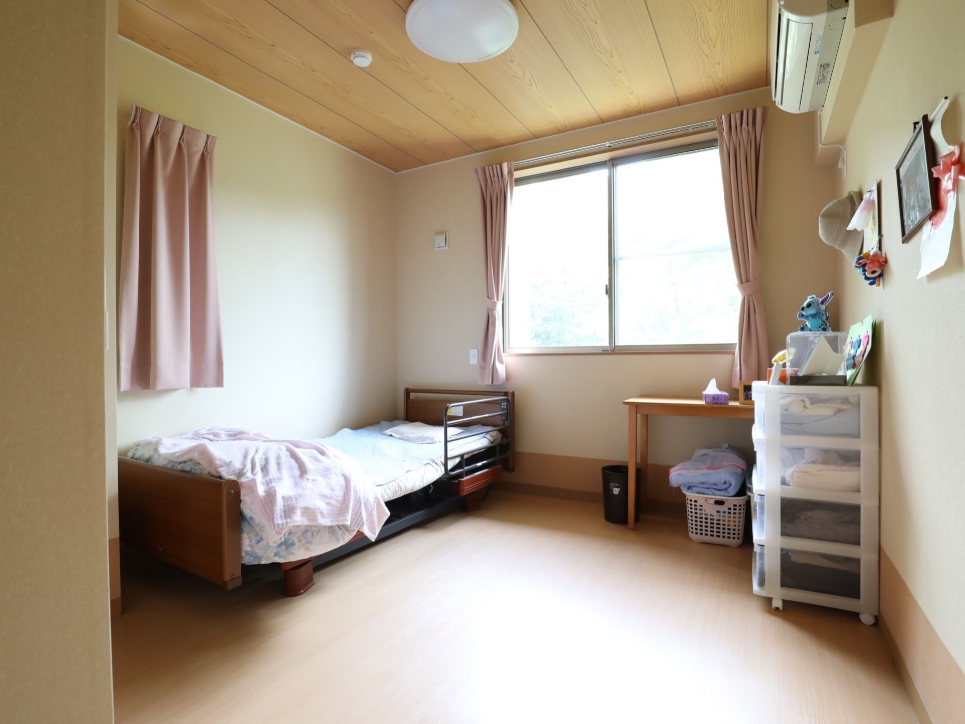 窓が大きく外から自然光が差し込んでいる。ベッドは可動式になっているので起き上がる動作を無理なく行える。空調設備もあるので快適に過ごせる。