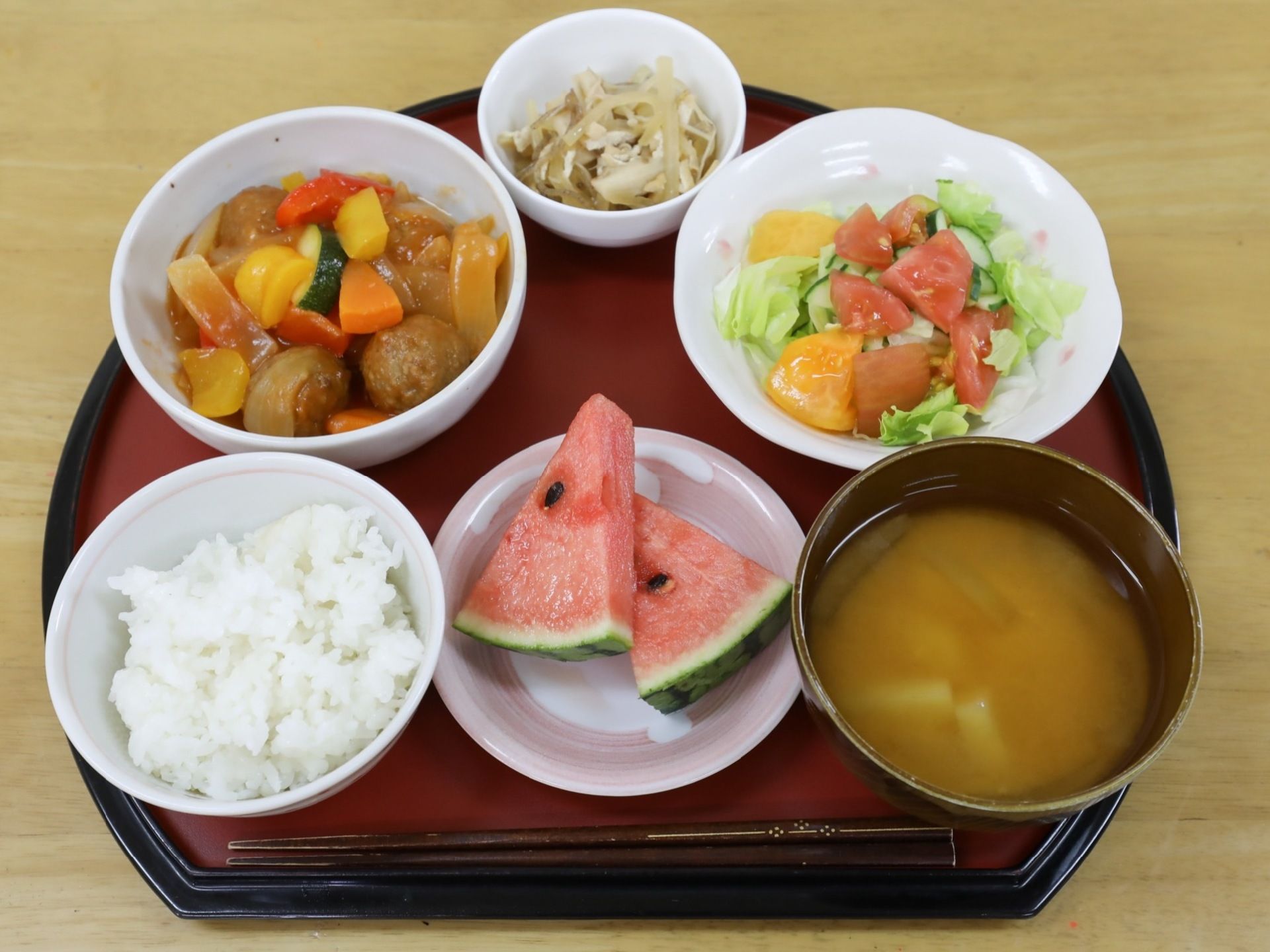 この日の食事は、ご飯とお味噌汁に酢豚とサラダ、和え物の３品のおかず、それにスイカのデザートが添えられている。