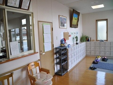 壁沿いにはＬ字型で扉付きの下駄箱が並んでいる。下駄箱の上には観葉植物などが飾られており、壁には絵画が展示されている。