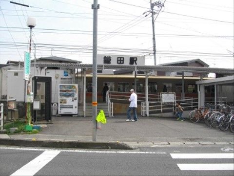 駅の外観である。手前に横断歩道があり、右向こうに駐輪場がある。駅のホームへは階段に加えスロープが設置されている。