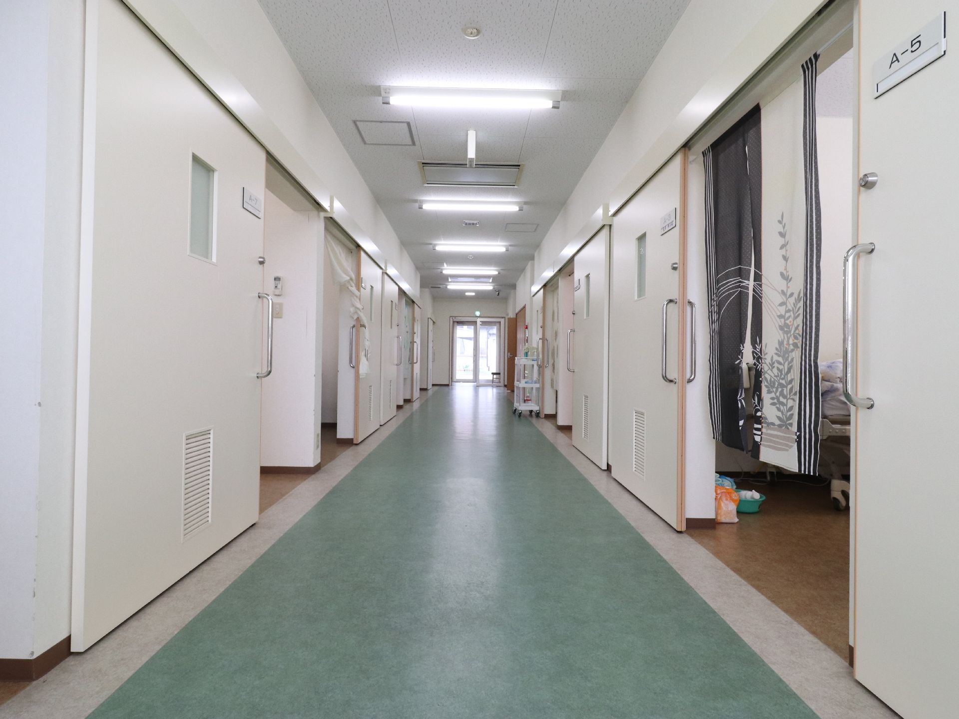 緑色をした床の両側には部屋の個室が並んでいる。A-5と番号か書かれた札がある部屋には暖簾が掛かっている。