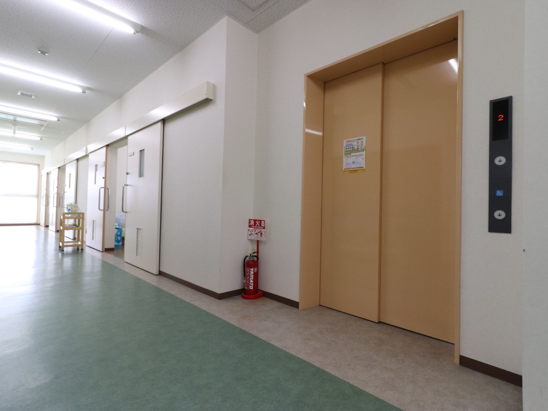 オレンジ色の大きめのエレベーターが1基ある。その横に消火器1つが設置されている。個室もいくつかある。