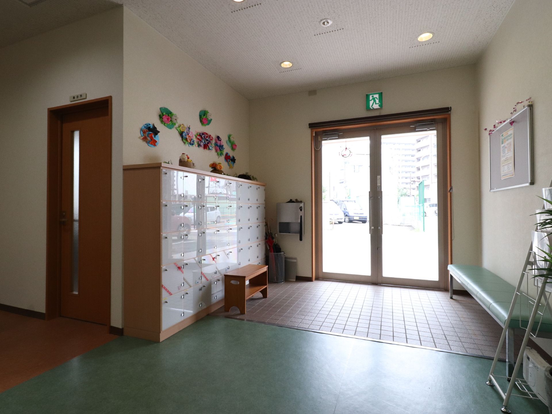 施設玄関には大きな靴箱と木製の椅子、緑色の長椅子が置かれている。車いすを利用している方もスムーズに動ける広いスペースになっている。
