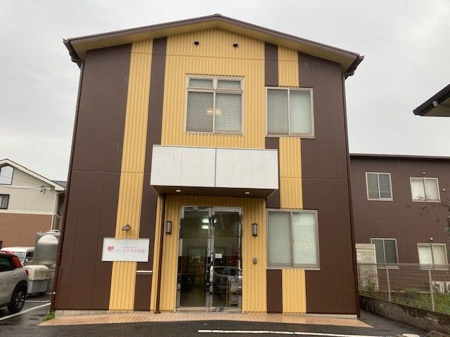 施設外観は全体的に茶系になっている。屋根が入り口についていて、施設の看板もある。何台かの車が止められるようになっている。