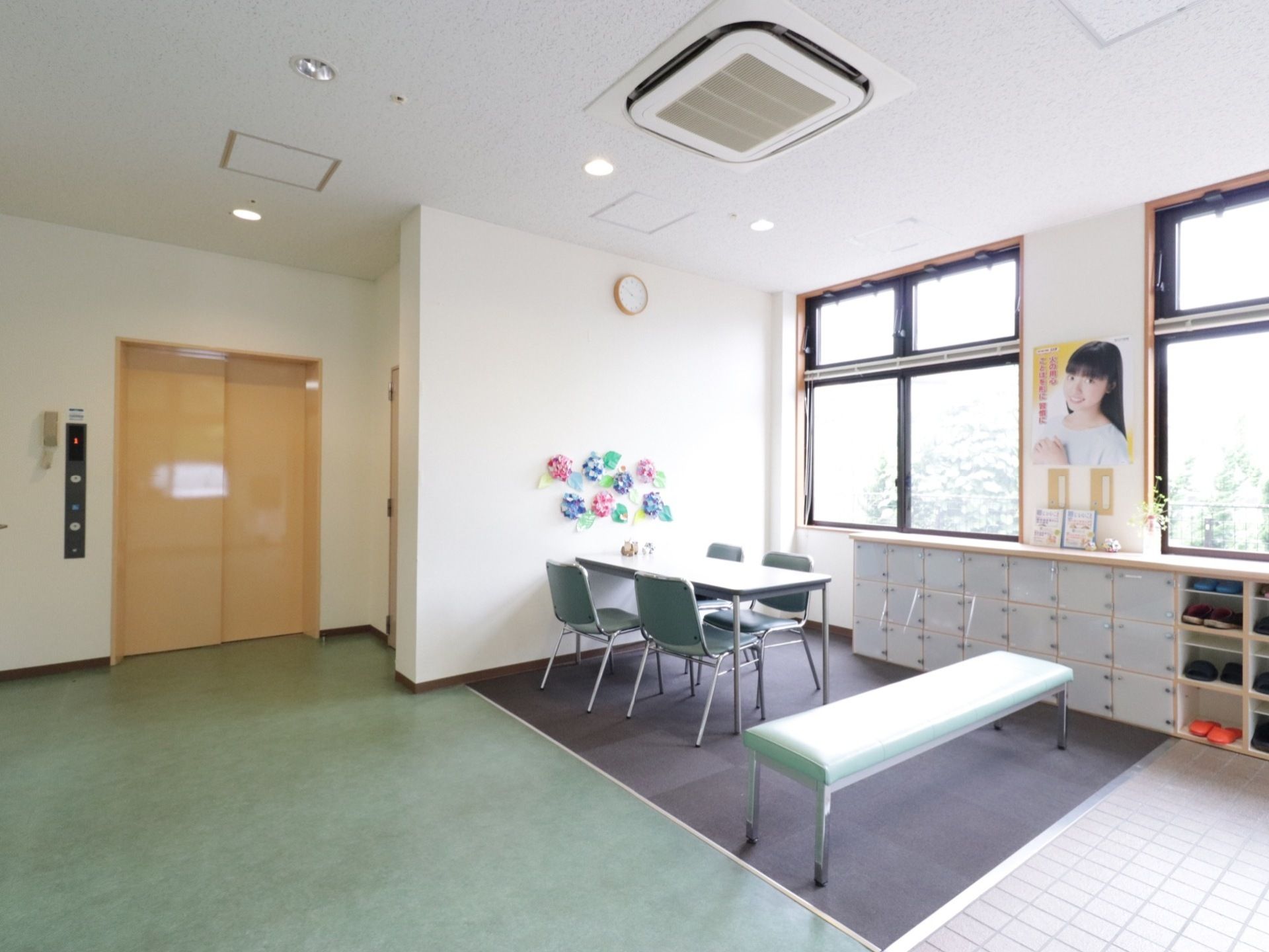 スリッパの入っている棚と、蓋つきの棚がある。緑色の長椅子は、靴を履き替える際に利用できる位置に設置してある。
