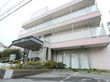 施設は３階建てである。玄関には手すりが取りつけられている。１階のガラス戸にはカーテンがかけられている。