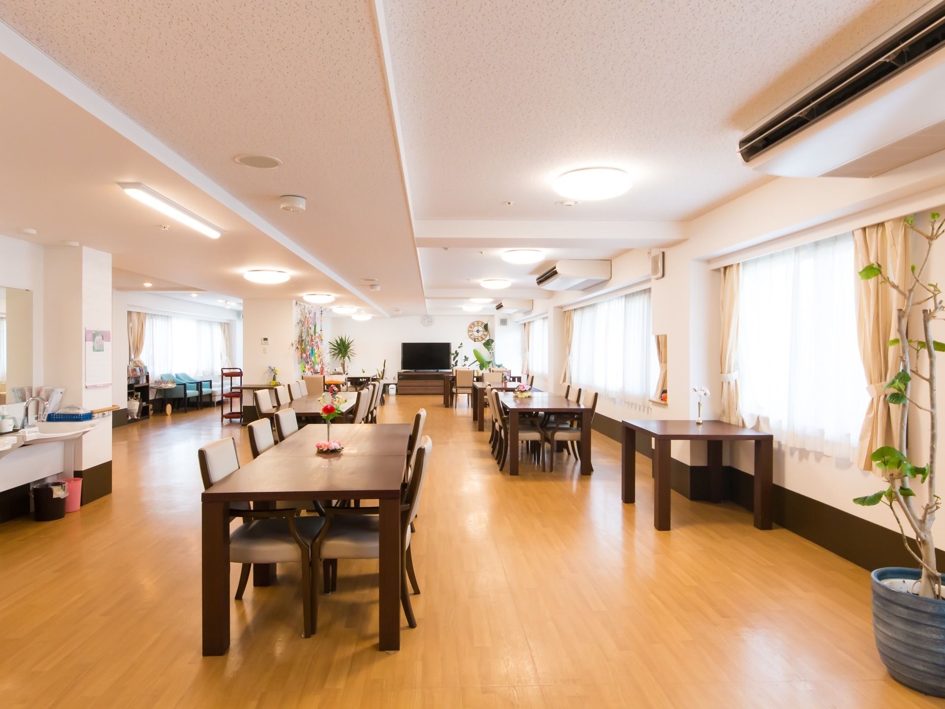 広々とした開放感あふれる食堂である。両側の窓からは日射しが差し込んでいる。大型液晶テレビや６人掛けのダイニングテーブルが完備されている。