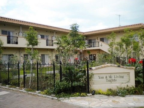 ２階建てのクリーム色の建物、手前には黒いお洒落な柵がある外観