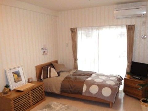 大きな窓があり、ベッド、テレビ、エアコンが設備されている居住空間